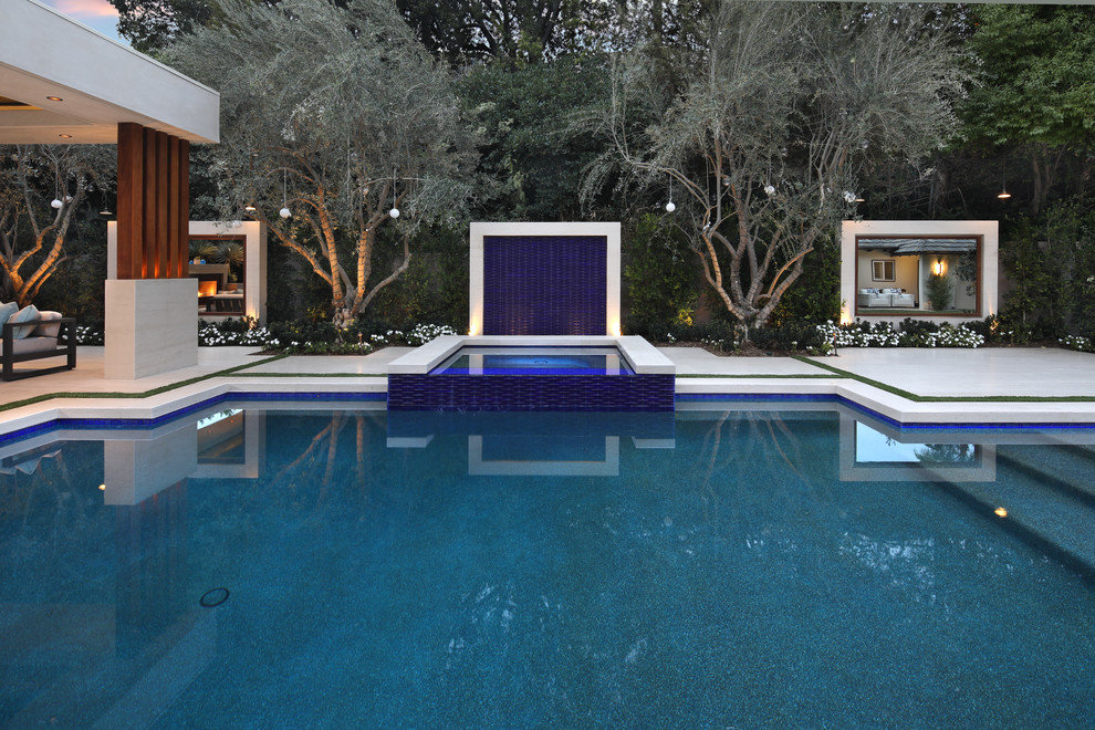 Diseño de piscina con fuente actual grande rectangular en patio trasero con adoquines de piedra natural