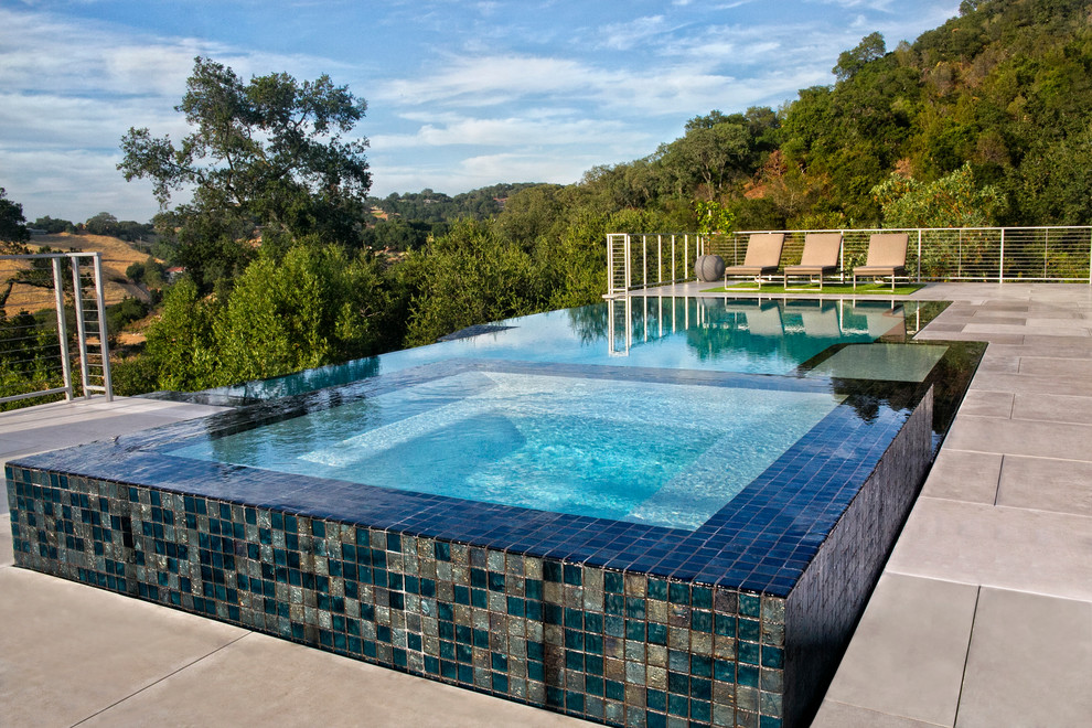 Aménagement d'une grande piscine à débordement et arrière moderne rectangle avec du carrelage.