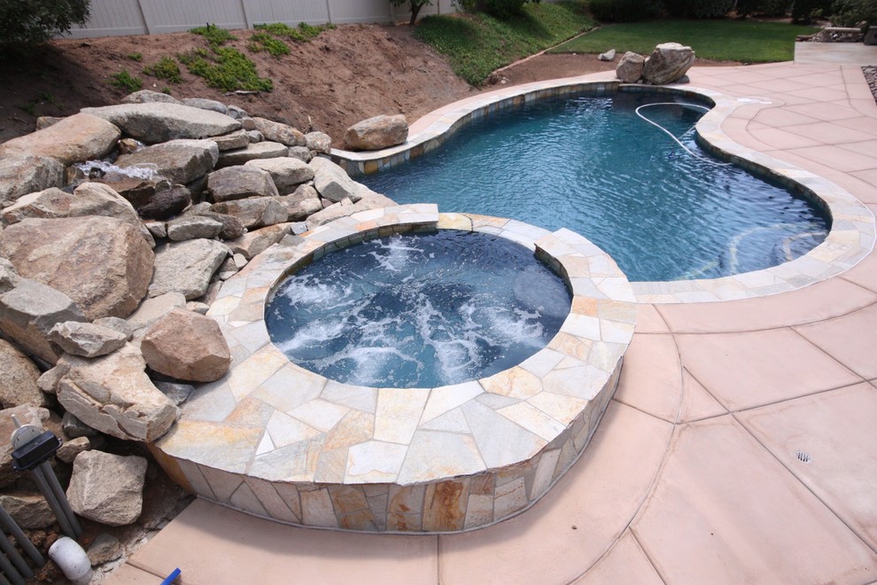 Small classic back custom shaped hot tub in San Diego with concrete slabs.