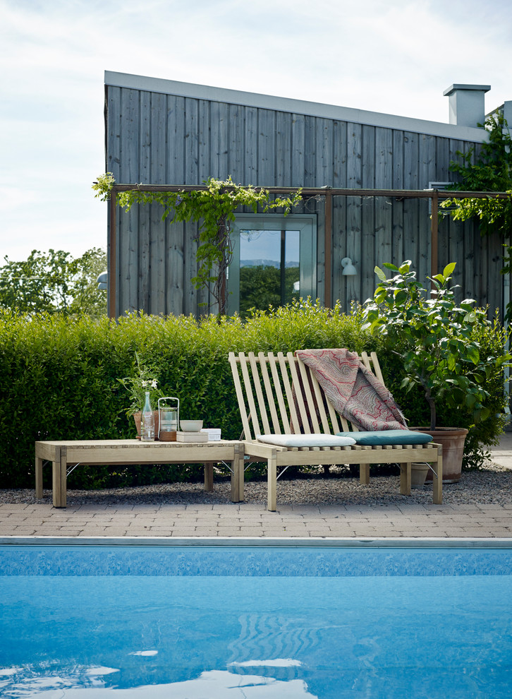 Ejemplo de piscina elevada escandinava de tamaño medio rectangular con adoquines de ladrillo