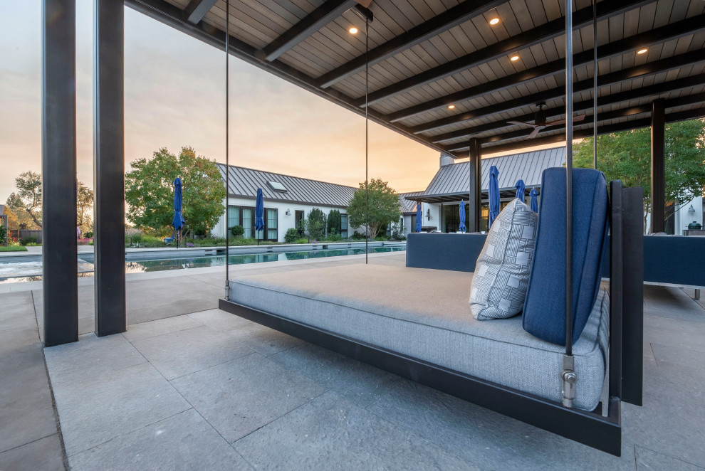Modelo de piscina moderna grande rectangular en patio trasero con adoquines de hormigón