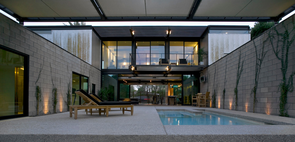 Modelo de piscinas y jacuzzis alargados modernos de tamaño medio rectangulares en patio con losas de hormigón