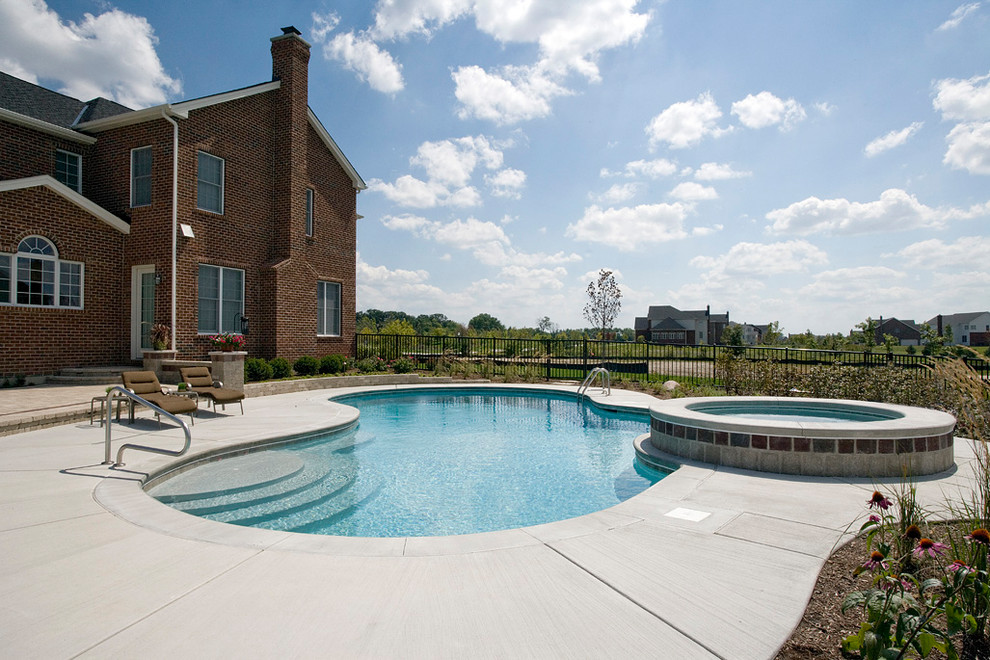 Cette photo montre une piscine naturelle et arrière chic en forme de haricot de taille moyenne avec un bain bouillonnant et une dalle de béton.