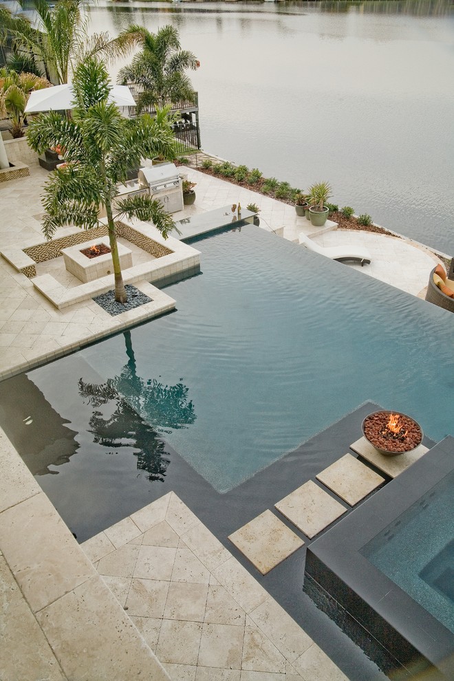 Aménagement d'une piscine à débordement et arrière contemporaine de taille moyenne et sur mesure avec des pavés en pierre naturelle.
