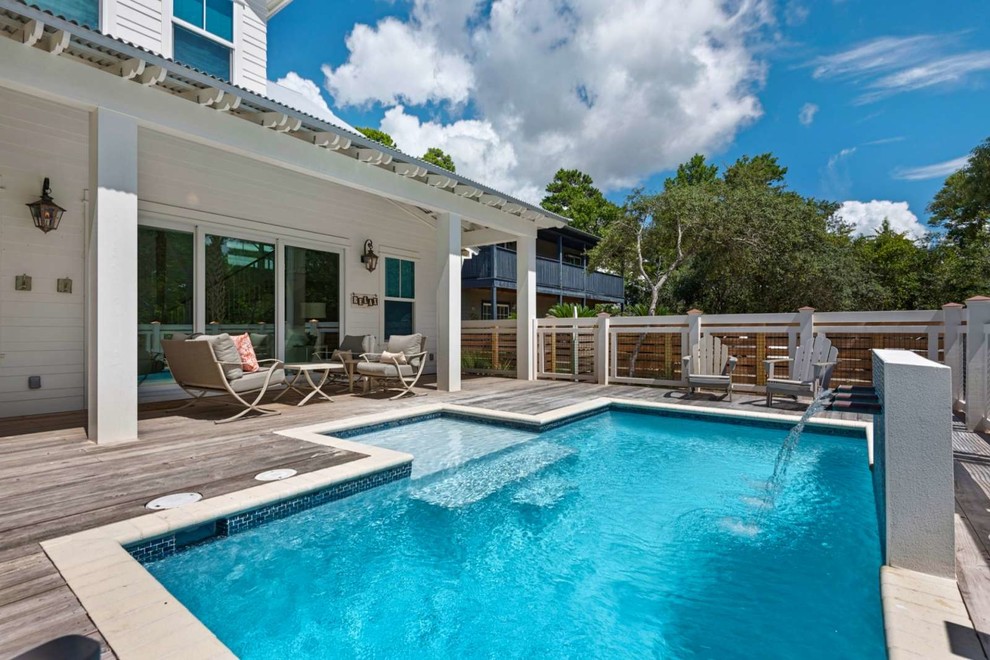 Cette image montre une piscine arrière marine de taille moyenne et sur mesure avec un point d'eau et une terrasse en bois.