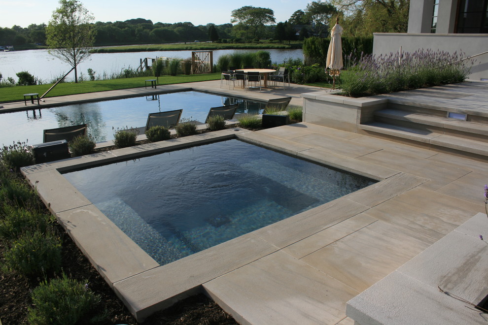 Ejemplo de piscinas y jacuzzis alargados actuales de tamaño medio rectangulares en patio trasero con adoquines de piedra natural