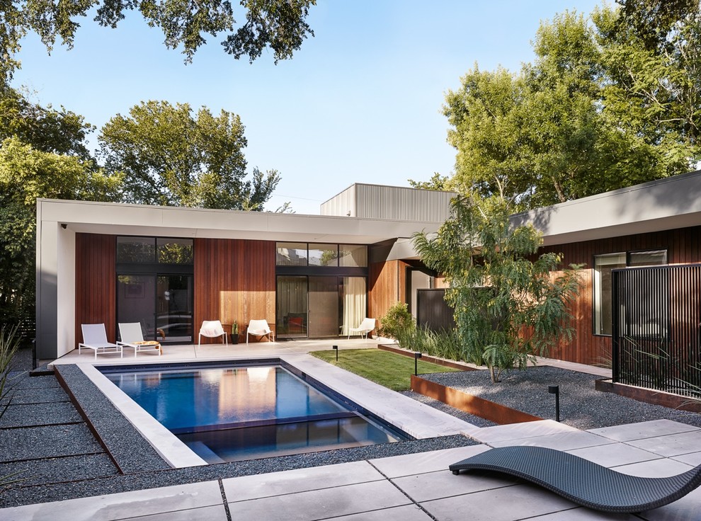 На фото: прямоугольный бассейн на заднем дворе в современном стиле с покрытием из бетонных плит с