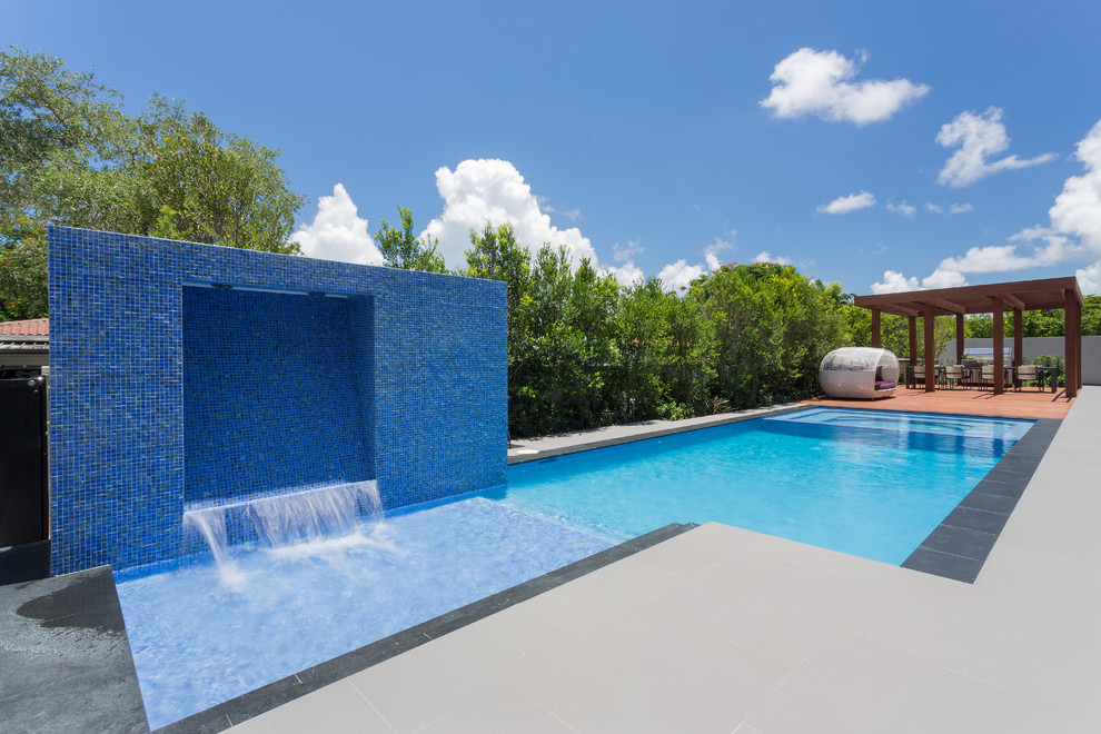 На фото: спортивный, прямоугольный бассейн среднего размера на заднем дворе в современном стиле с фонтаном и покрытием из декоративного бетона с