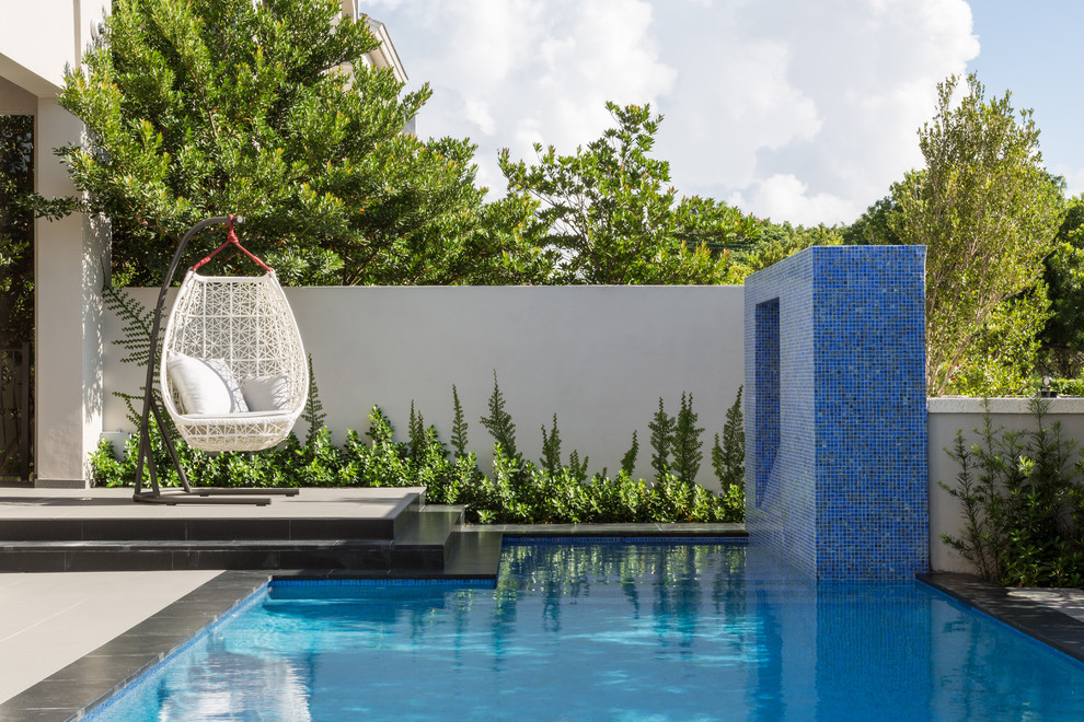 Immagine di una piscina monocorsia minimal rettangolare di medie dimensioni e dietro casa con fontane