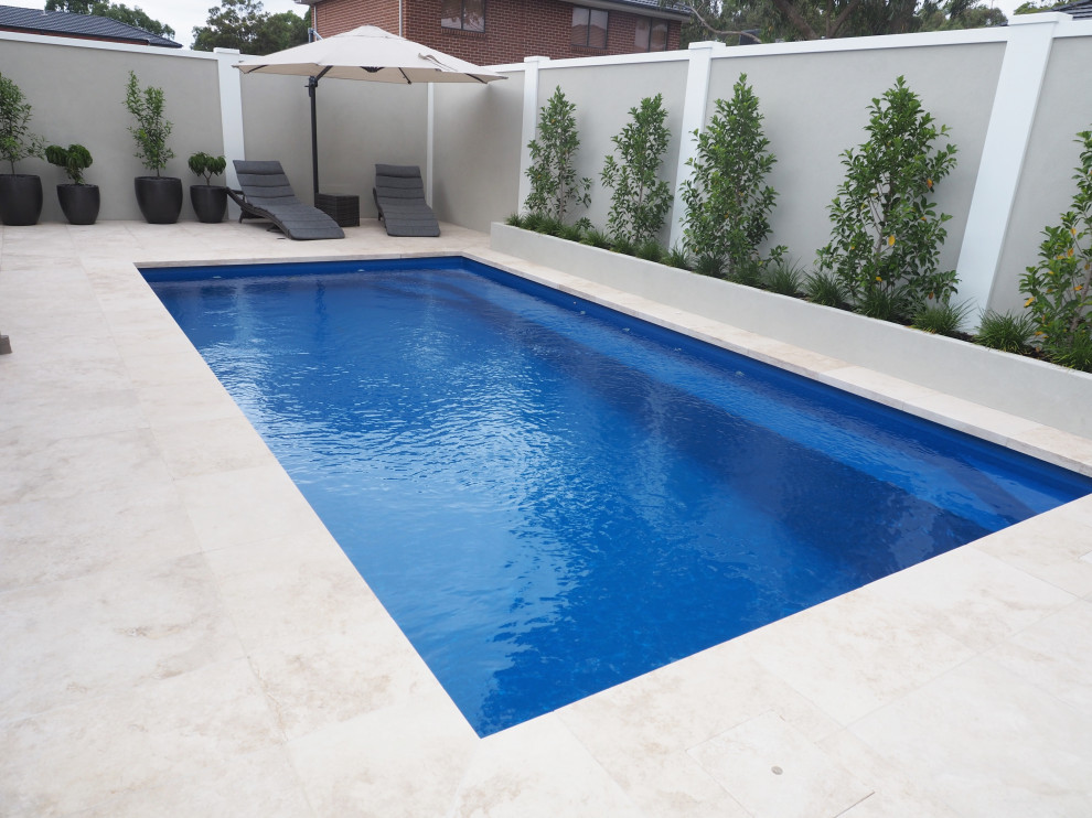 Réalisation d'un piscine avec aménagement paysager arrière minimaliste de taille moyenne et rectangle avec des pavés en pierre naturelle.