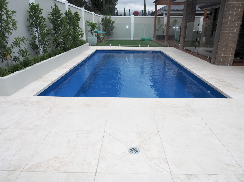 Diseño de piscina natural moderna de tamaño medio rectangular en patio trasero con paisajismo de piscina y adoquines de piedra natural