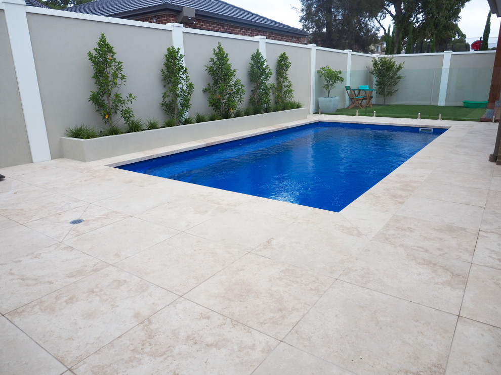 Esempio di una piscina naturale minimalista rettangolare di medie dimensioni e dietro casa con paesaggistica bordo piscina e pavimentazioni in pietra naturale