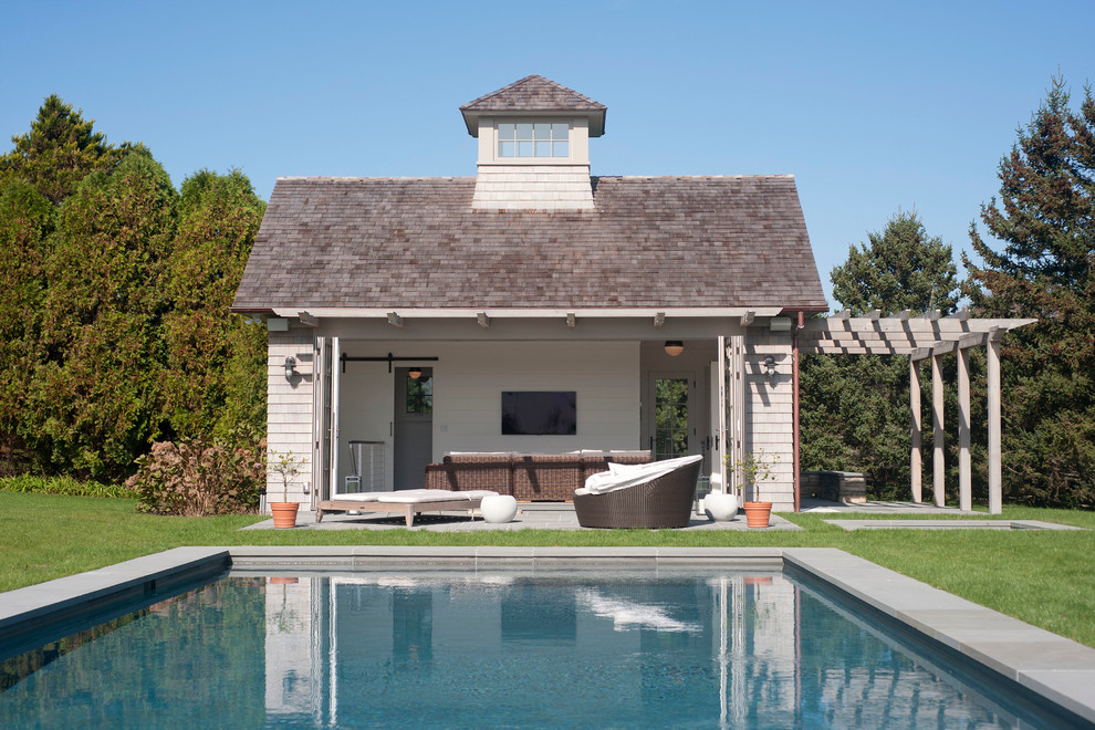 Diseño de casa de la piscina y piscina costera rectangular en patio trasero con adoquines de hormigón