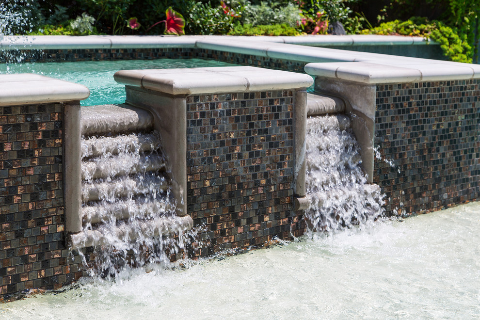 Foto de piscina con fuente alargada tradicional de tamaño medio rectangular en patio trasero con adoquines de piedra natural