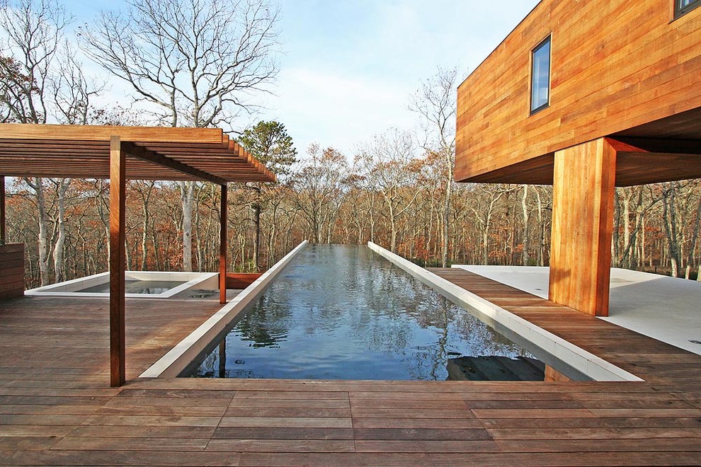 Mountain style rectangular infinity hot tub photo in New York with decking