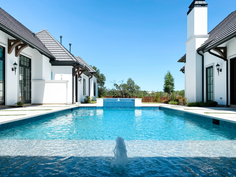 Immagine di un'ampia piscina chic rettangolare dietro casa con una vasca idromassaggio e pavimentazioni in pietra naturale