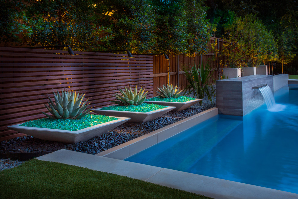 Foto di una piscina moderna rettangolare di medie dimensioni e dietro casa con fontane e pedane