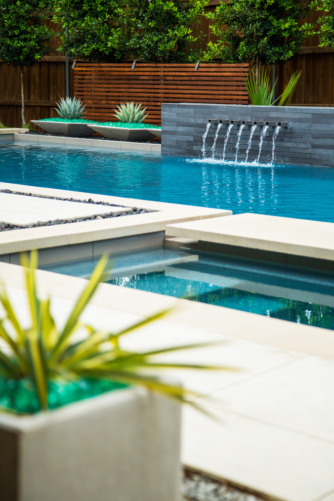 Immagine di una piscina minimalista rettangolare di medie dimensioni e dietro casa con fontane e pavimentazioni in cemento