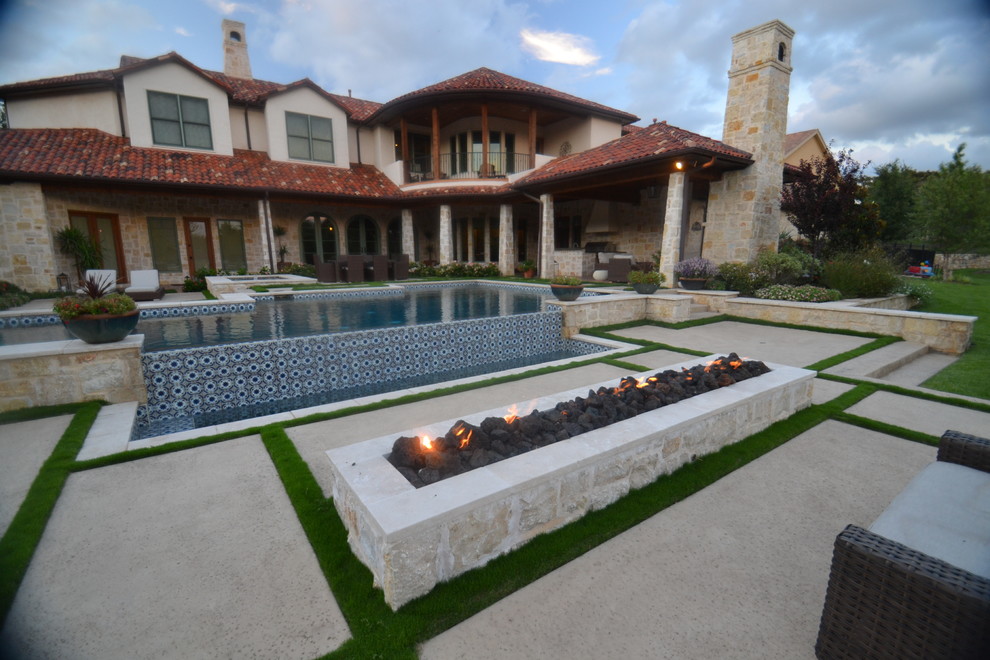 Modelo de piscina infinita actual grande rectangular en patio trasero con losas de hormigón