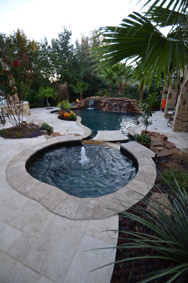 Design ideas for a medium sized world-inspired back custom shaped natural swimming pool in Dallas with a water feature and natural stone paving.