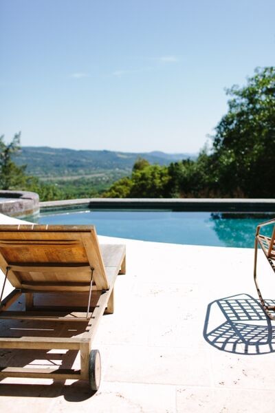 Immagine di una grande piscina a sfioro infinito stile americano personalizzata dietro casa con una vasca idromassaggio e pavimentazioni in pietra naturale