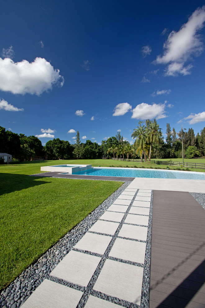 Идея дизайна: большой спортивный, прямоугольный бассейн на заднем дворе в современном стиле с джакузи и покрытием из каменной брусчатки