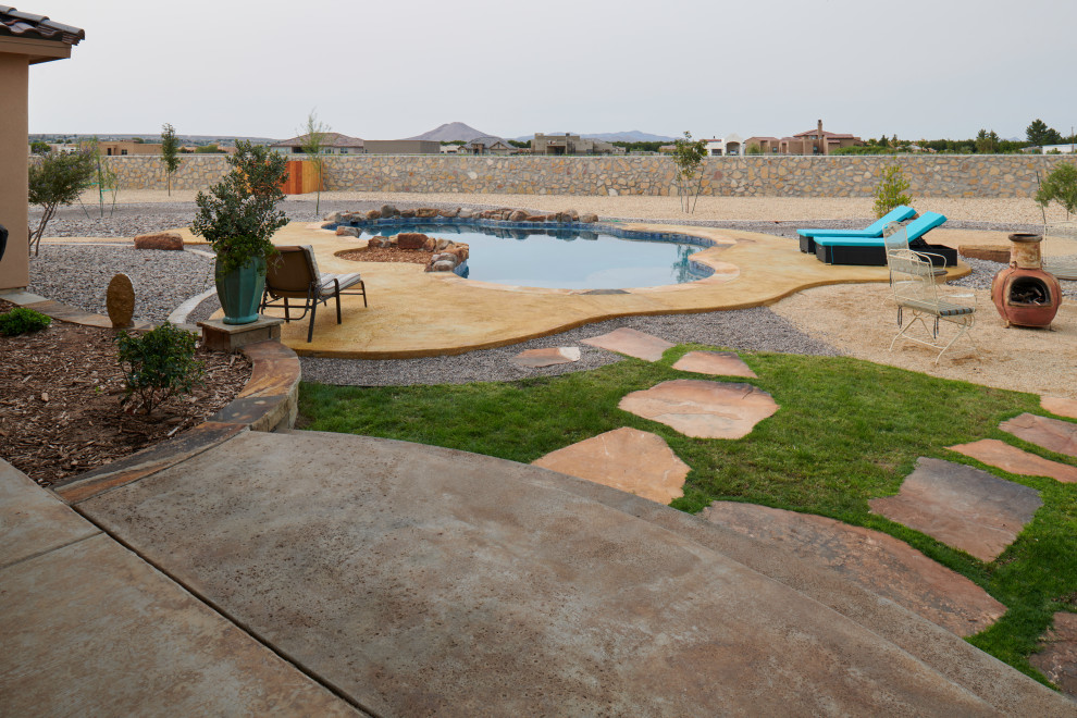 Réalisation d'un grand piscine avec aménagement paysager arrière sud-ouest américain sur mesure avec une dalle de béton.