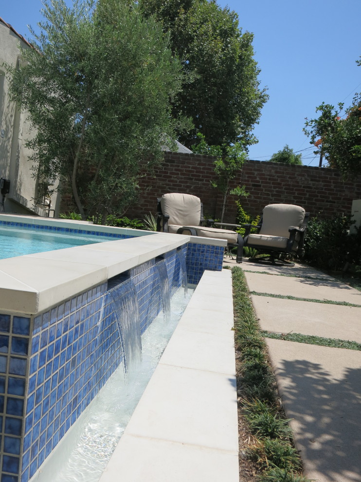 Ejemplo de piscina con fuente alargada contemporánea pequeña rectangular en patio trasero con suelo de baldosas