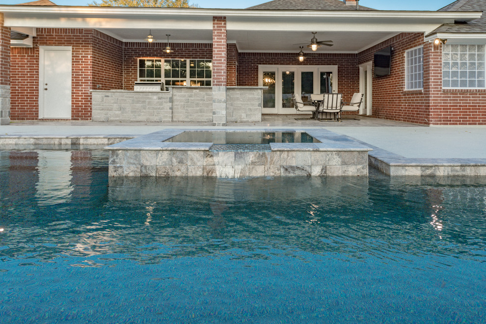 Exemple d'une piscine arrière tendance de taille moyenne et sur mesure avec un bain bouillonnant et des pavés en pierre naturelle.