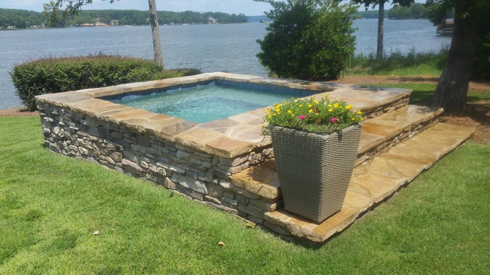 Modelo de piscinas y jacuzzis elevados clásicos renovados pequeños rectangulares en patio trasero con adoquines de piedra natural