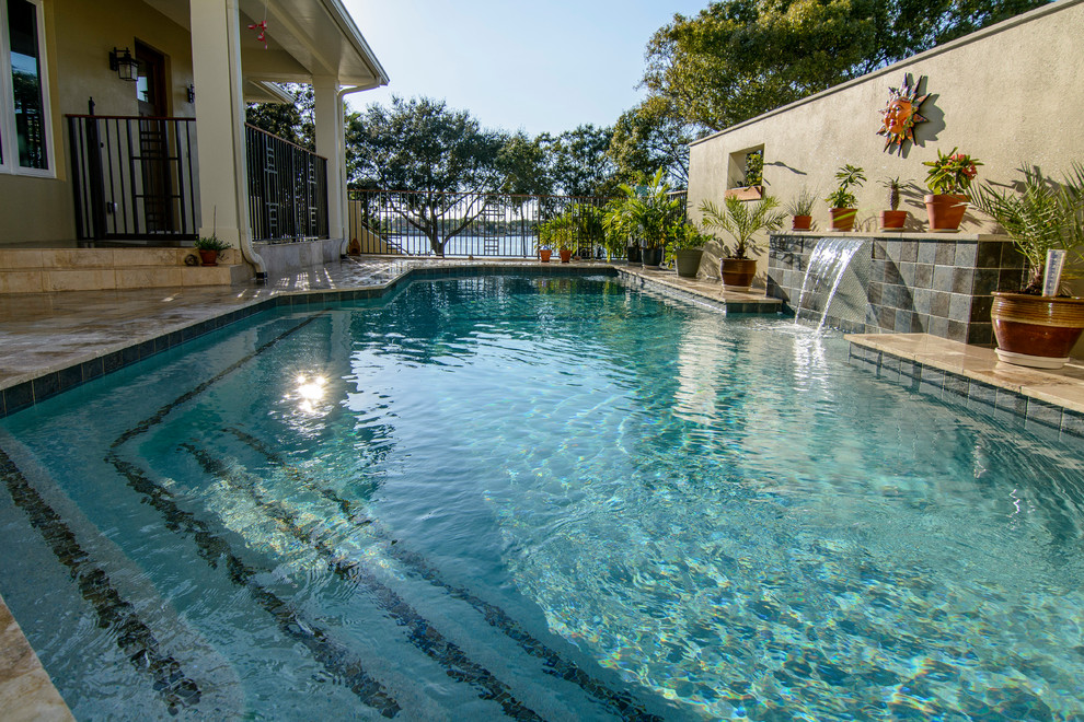 Immagine di una grande piscina monocorsia design rettangolare dietro casa con una vasca idromassaggio