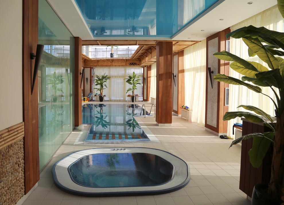 На фото: большой бассейн произвольной формы в доме в современном стиле с домиком у бассейна и покрытием из плитки