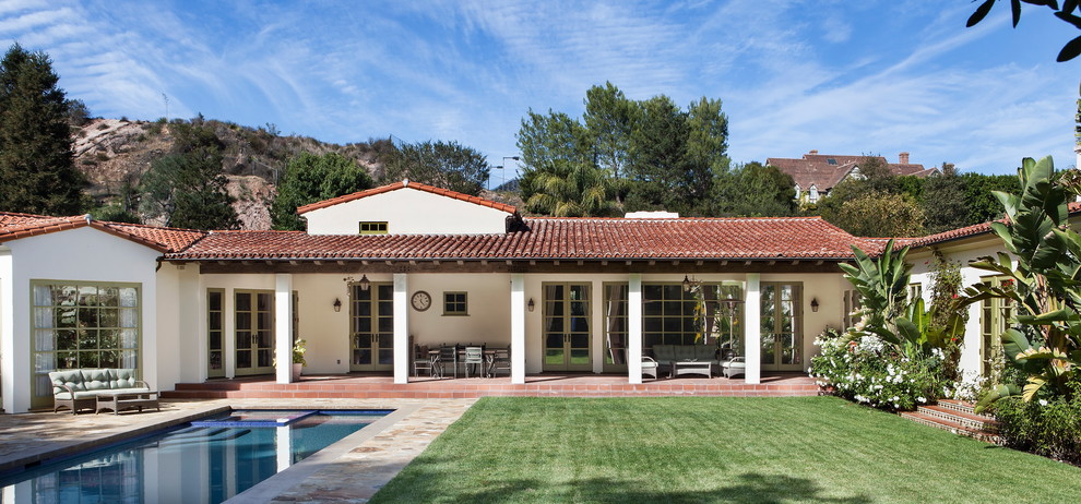 Imagen de piscina alargada mediterránea grande rectangular en patio con suelo de baldosas