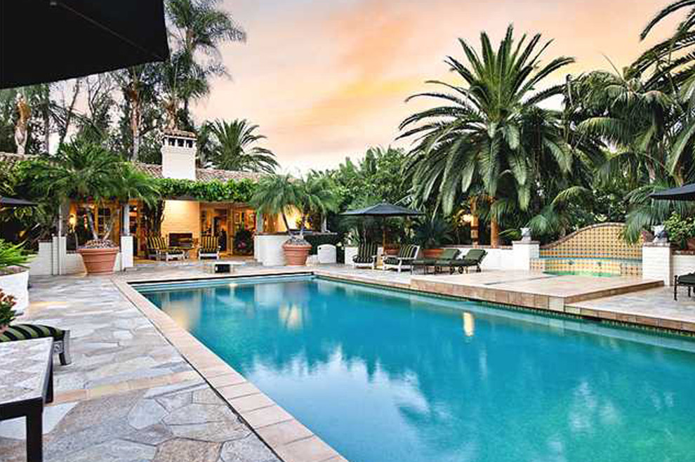 Ejemplo de piscinas y jacuzzis alargados exóticos grandes rectangulares en patio trasero con adoquines de piedra natural