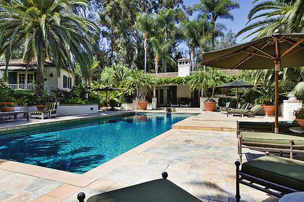 Immagine di una grande piscina monocorsia tropicale rettangolare dietro casa con pavimentazioni in pietra naturale