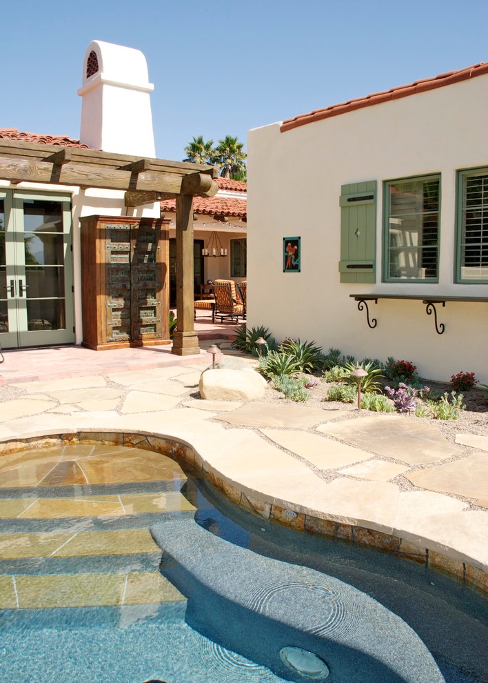 Photo of a mediterranean back kidney-shaped hot tub in San Diego with natural stone paving.