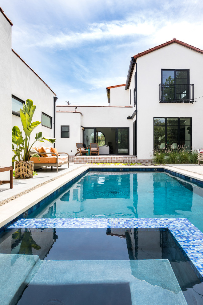 На фото: прямоугольный бассейн среднего размера на заднем дворе в средиземноморском стиле с джакузи и покрытием из бетонных плит