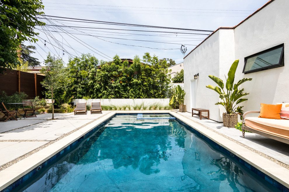 На фото: прямоугольный бассейн среднего размера на заднем дворе в средиземноморском стиле с джакузи и покрытием из бетонных плит