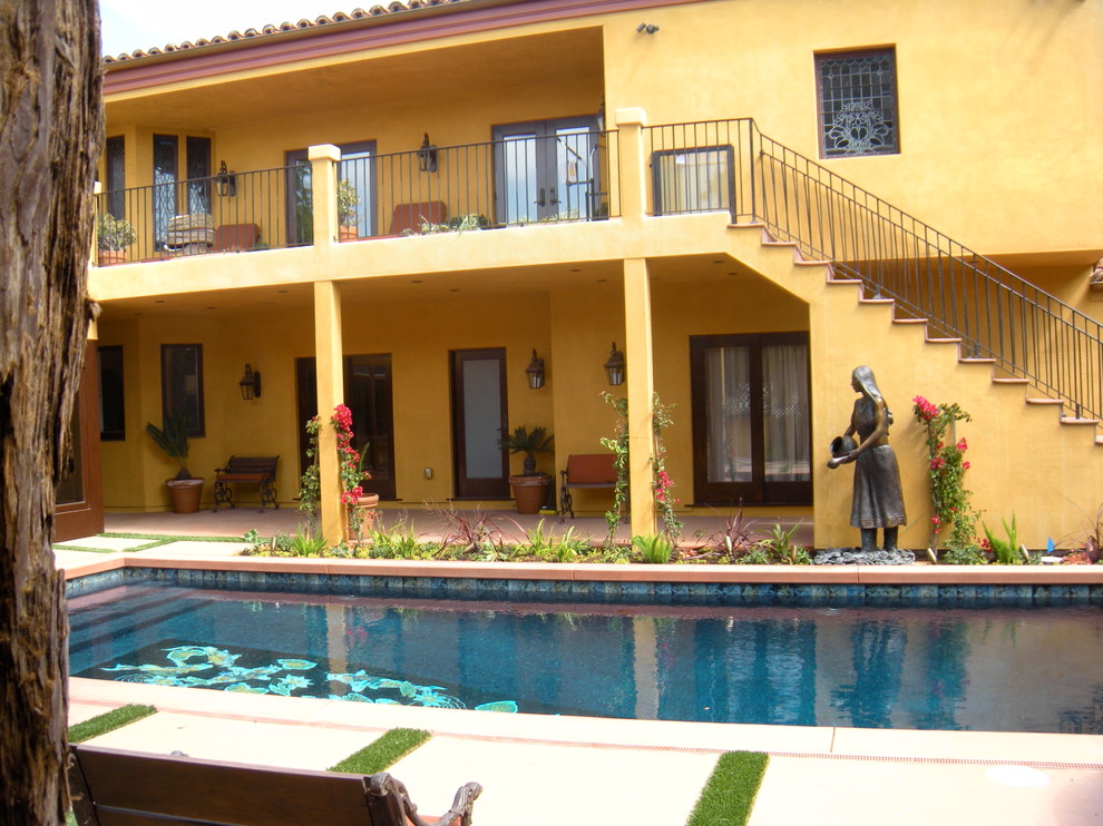На фото: большой прямоугольный бассейн на заднем дворе в средиземноморском стиле с покрытием из бетонных плит