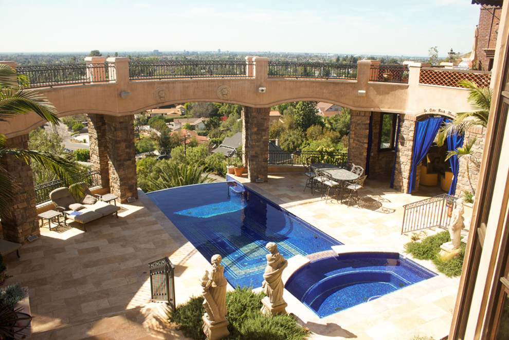 Cette image montre une piscine à débordement méditerranéenne de taille moyenne et rectangle avec un bain bouillonnant, une cour et du carrelage.