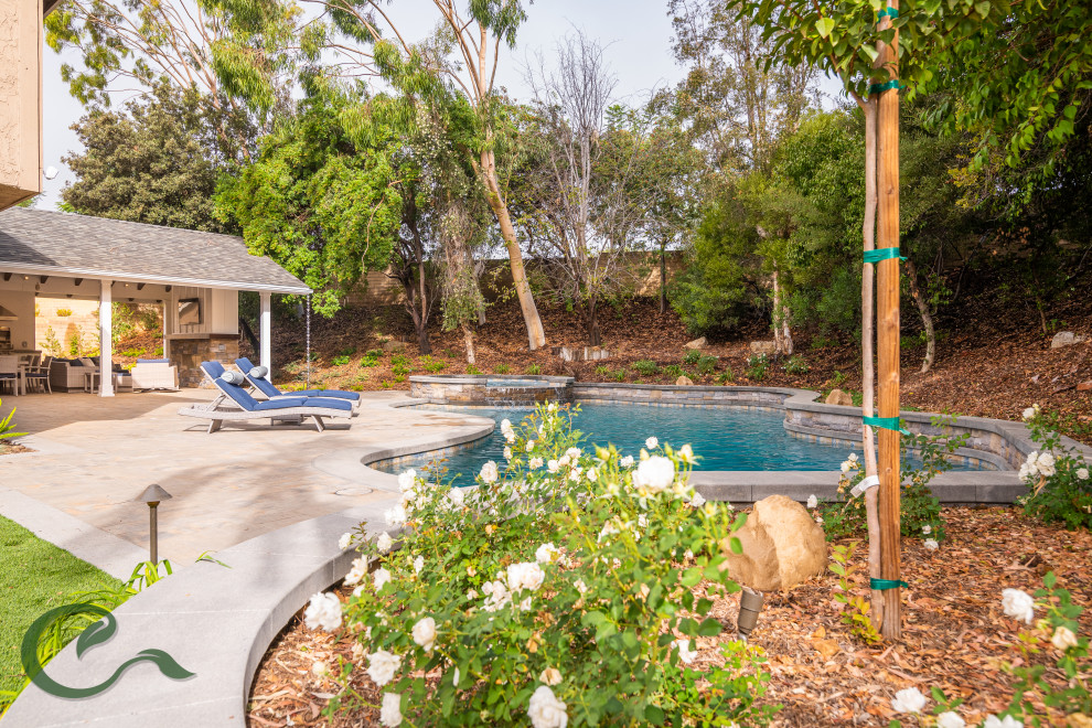 Ispirazione per una piscina naturale tradizionale personalizzata di medie dimensioni e dietro casa con una vasca idromassaggio e pavimentazioni in cemento