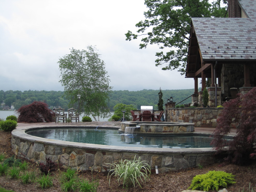 Inspiration pour une grande piscine arrière et naturelle craftsman ronde avec un bain bouillonnant et une terrasse en bois.
