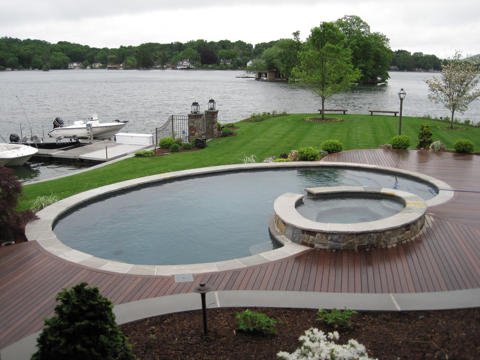 Идея дизайна: большой круглый, естественный бассейн на заднем дворе в стиле кантри с джакузи и настилом