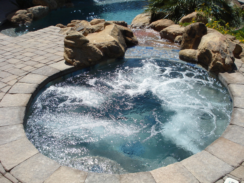 Ejemplo de piscinas y jacuzzis tradicionales redondeados en patio trasero con suelo de baldosas