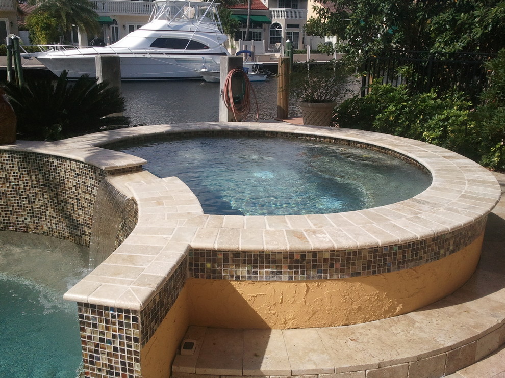 Foto de piscinas y jacuzzis actuales de tamaño medio redondeados en patio trasero con adoquines de piedra natural