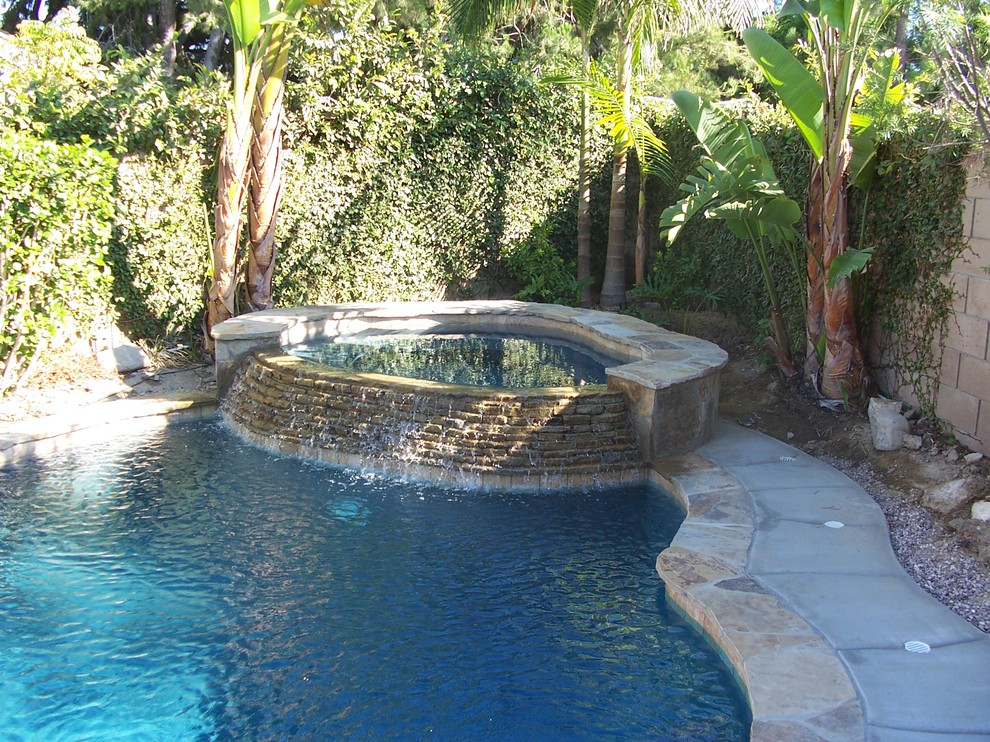 Inspiration for a mid-sized mediterranean backyard stone and round hot tub remodel in Miami