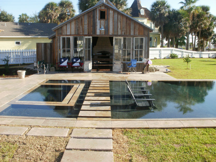 Immagine di una grande piscina monocorsia industriale rettangolare dietro casa con una vasca idromassaggio e pavimentazioni in cemento