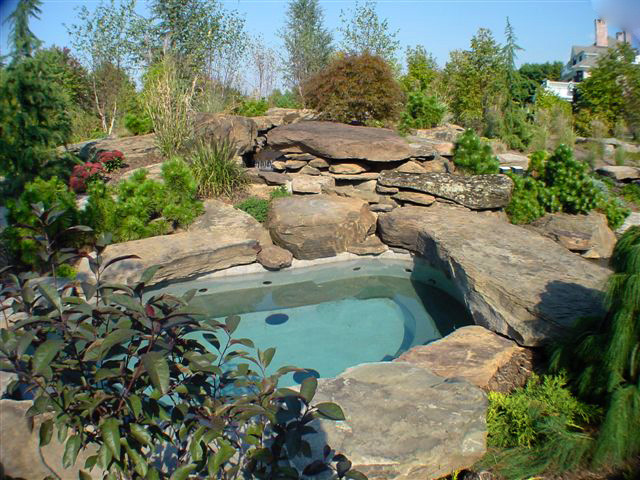 Aménagement d'une piscine arrière craftsman en forme de haricot avec un bain bouillonnant et des pavés en pierre naturelle.