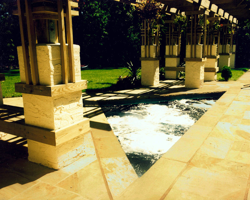 Foto di una piscina stile americano personalizzata di medie dimensioni e dietro casa con una vasca idromassaggio e pavimentazioni in pietra naturale