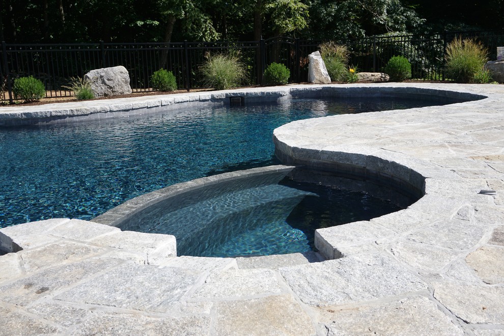 Foto di una piscina minimalista personalizzata di medie dimensioni e dietro casa con una vasca idromassaggio e pavimentazioni in pietra naturale